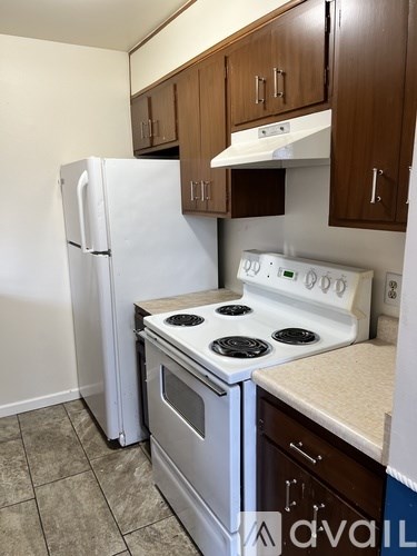A kitchen with a white fridge, white stove and brown cabinets.
