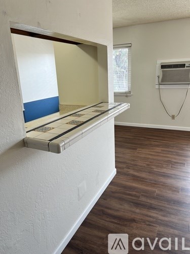A room with a white wall and a window with blinds.