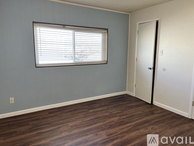 A room with a window and wooden flooring.