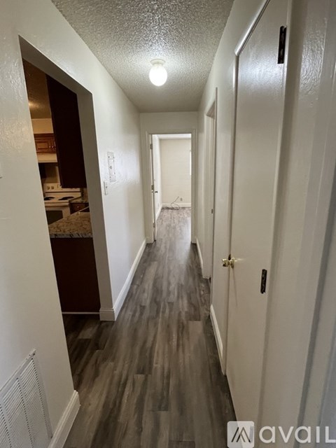 A long hallway with wood floors and white walls.