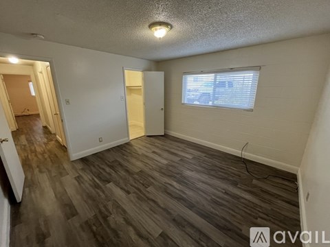 A room with wooden flooring and a window with blinds.