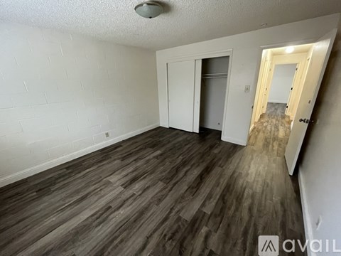 A room with wooden flooring and white walls, featuring a mirror and two doors.