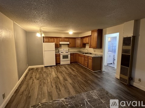 A kitchen with wooden floors and white appliances.