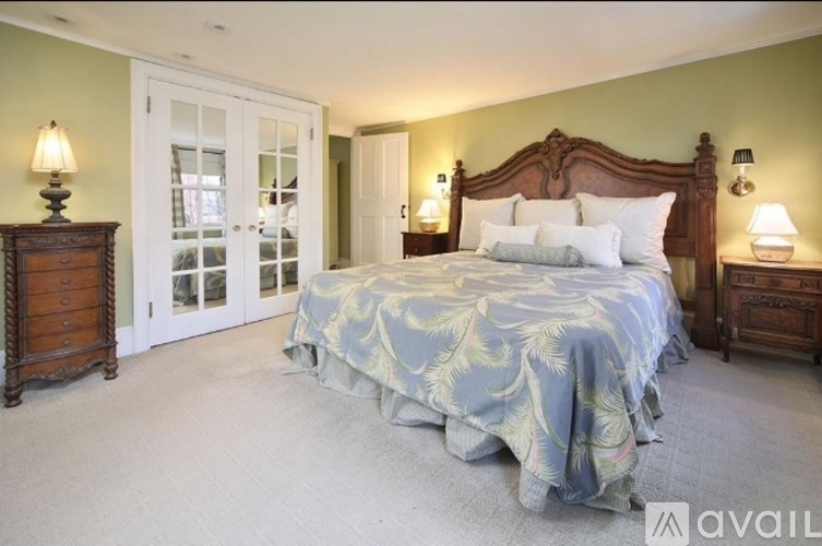 A bedroom with a large bed, two nightstands, and a dresser.