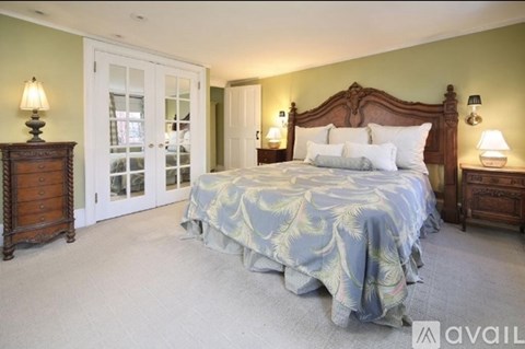 A bedroom with a large bed, two nightstands, and a dresser.