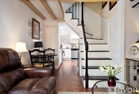 A living room with a brown leather couch and a wooden table with a lamp on it.
