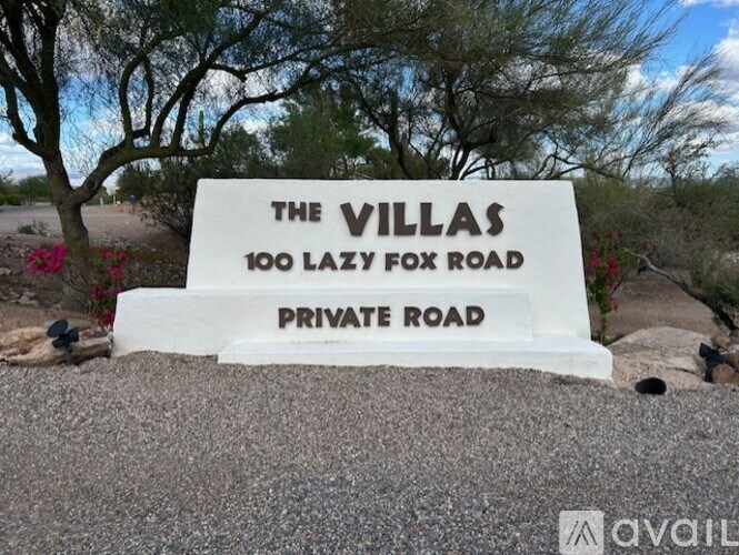 A sign that says "The Villas 100 Lazy Fox Road Private Road" is displayed in front of a tree.