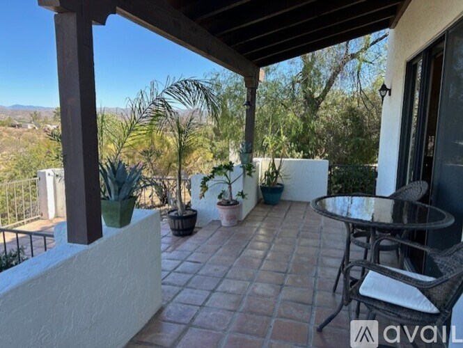 A patio with a table and chairs overlooking a mountainous landscape.