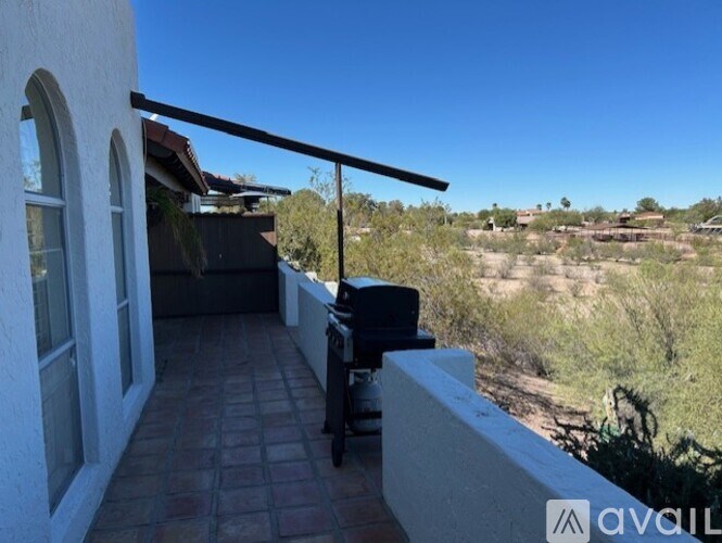 A balcony with a tiled floor and a table with chairs overlooks a desert landscape.