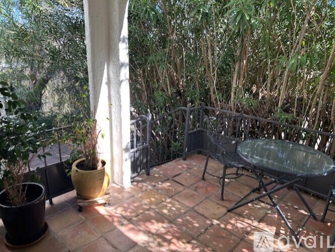 A patio with a table and chairs surrounded by trees.