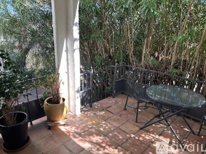 A patio with a table and chairs surrounded by trees.