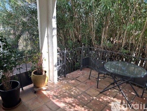 A patio with a table and chairs surrounded by trees.