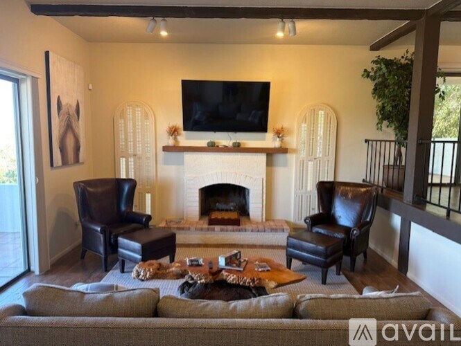 A living room with a fireplace and a television mounted above it.