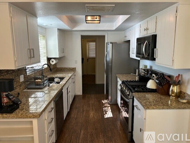 A kitchen with white cabinets and a granite countertop.