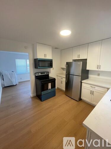 A kitchen with white cabinets and a wooden floor.