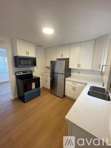 A kitchen with white cabinets and a wooden floor.