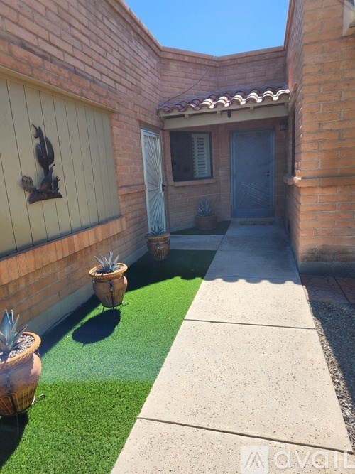 A small courtyard with a green lawn and a wall with a sculpture.