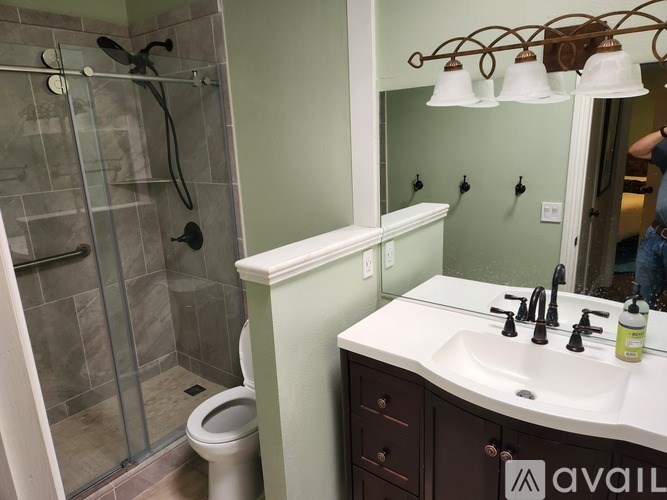 A bathroom with a white sink and a glass shower stall.