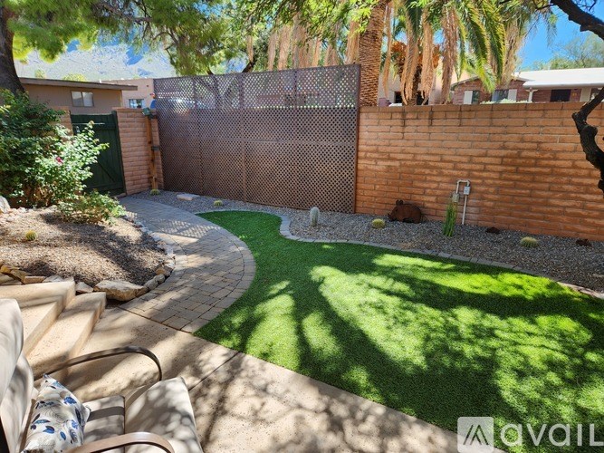A backyard with a fence, a small lawn, and a patio area.