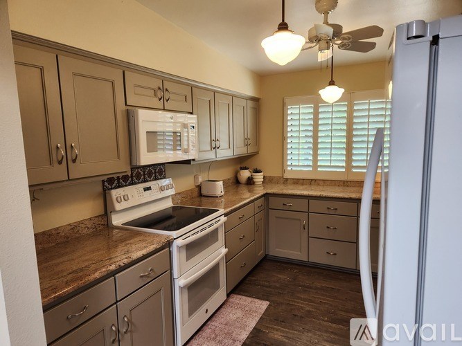 A kitchen with a white stove top oven and a white refrigerator.