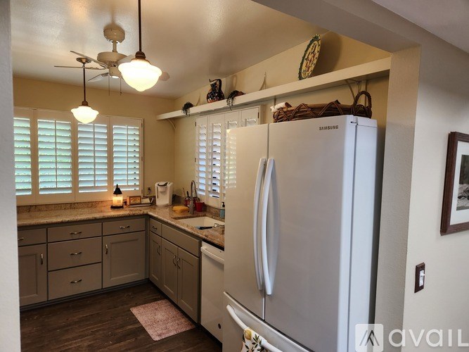 A kitchen with a white refrigerator and wooden floors.