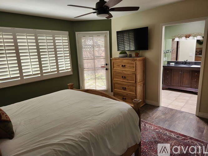 A bedroom with a bed, dresser, and window with blinds.
