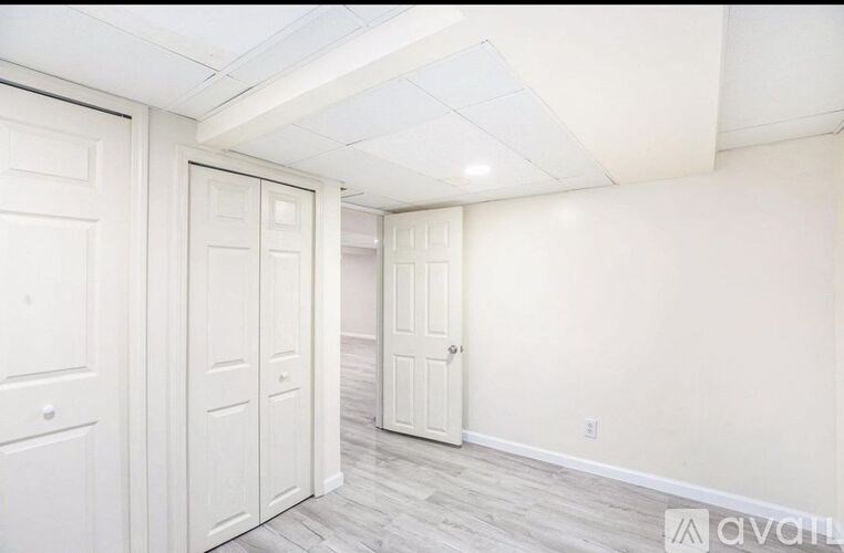 A room with white walls and a wooden floor with three doors.