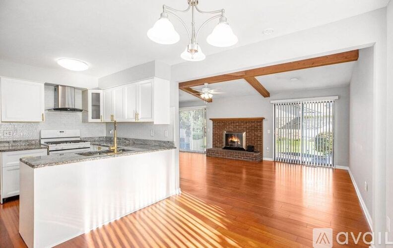 A modern kitchen with a large island and a fireplace in the living room.