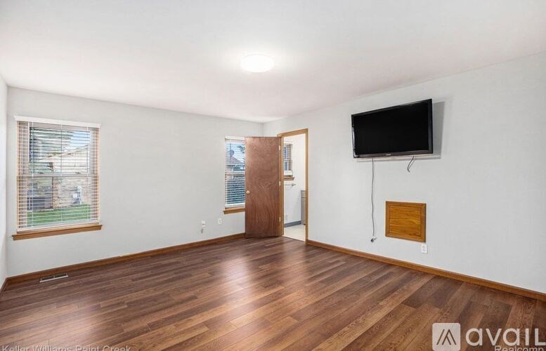 A room with wooden floors and a flat screen TV mounted on the wall.