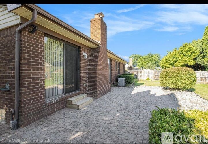 A brick house with a patio and a chimney.