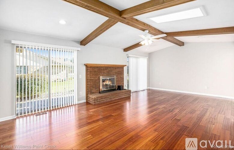 A spacious room with a fireplace and wooden floors.