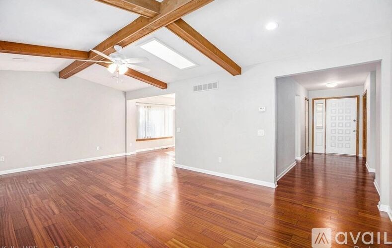A spacious room with wooden floors and a ceiling fan.