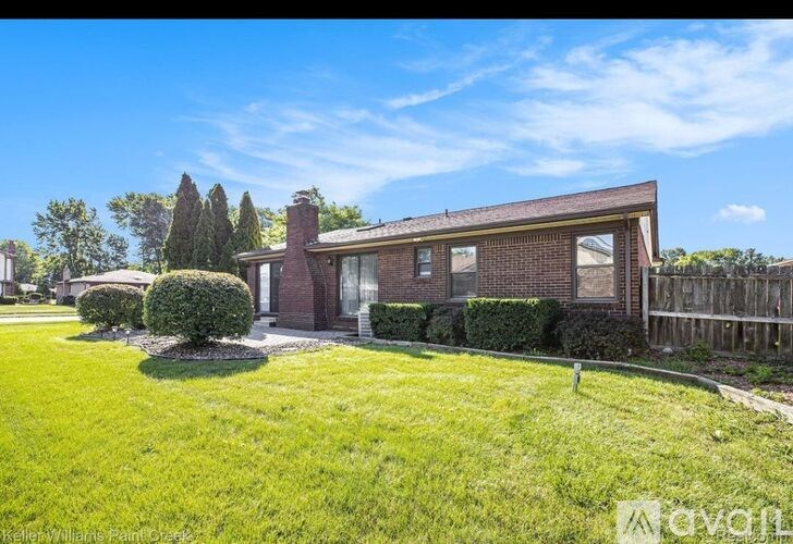 A house with a well-maintained lawn and a clear blue sky.