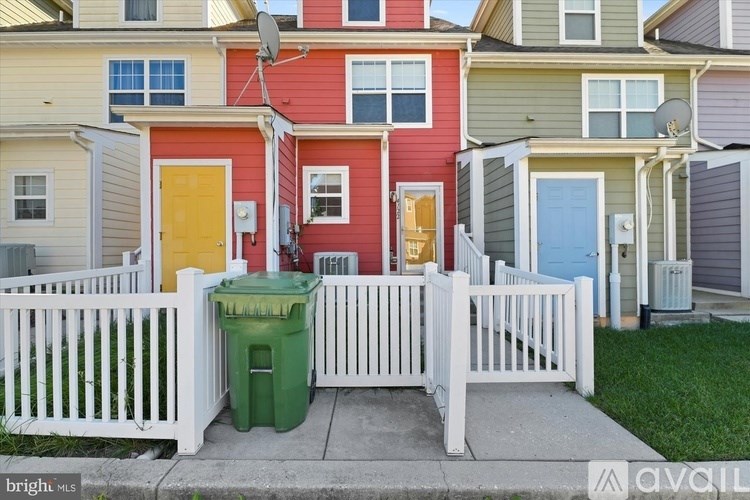 A row of houses with a green trash can in front.