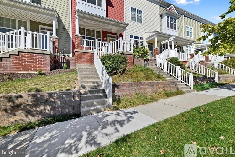 A row of houses with white railings and steps leading to the front doors.