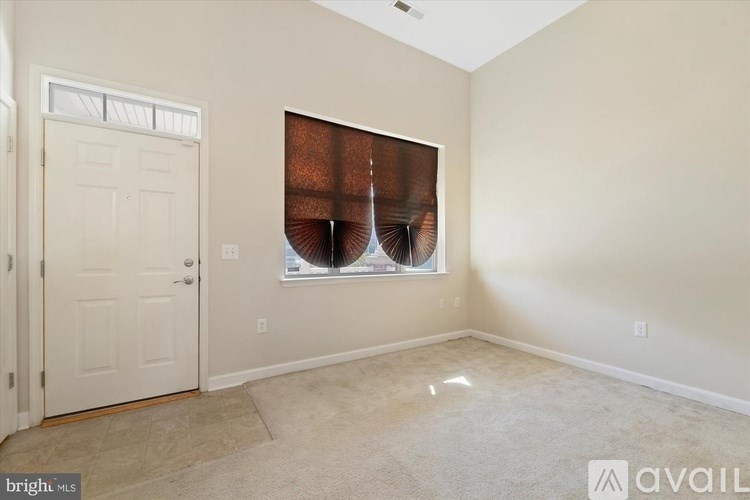 A room with a white door and a window with a brown curtain.