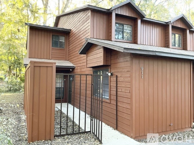 A brown wooden house with a black gate in front.