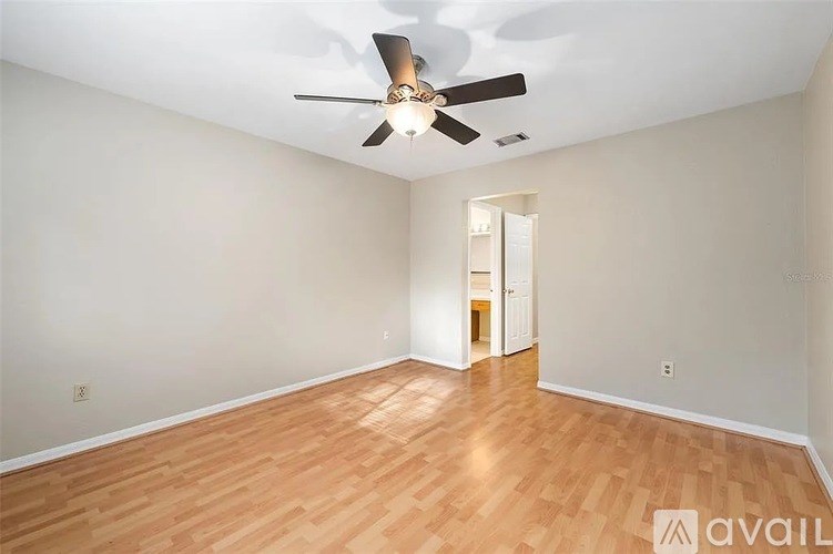 A room with a ceiling fan and wooden flooring.