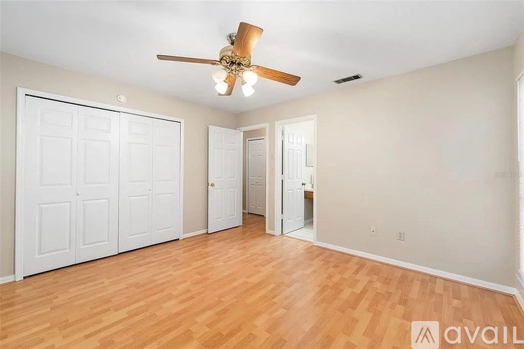 A room with a ceiling fan and wooden floors.
