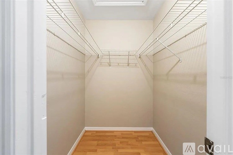 Empty walk-in closet with white walls and wooden floor.