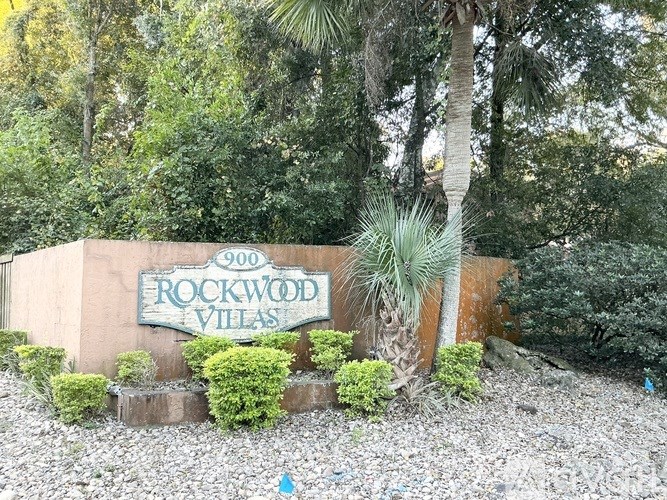 A sign that says "900 Rockwood Villas" is surrounded by plants and trees.