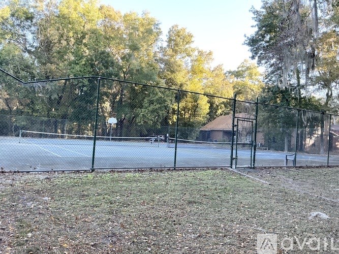 A tennis court surrounded by a fence and trees.