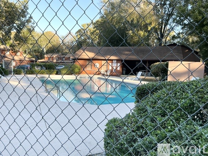 A chain link fence with a pool and house in the background.