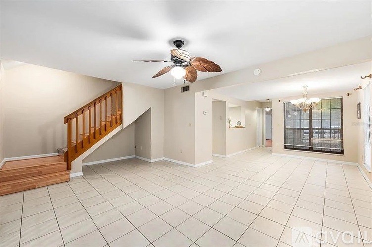 A spacious living room with a ceiling fan and a staircase.
