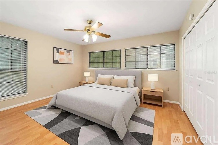 A bedroom with a bed, two lamps, and a ceiling fan.