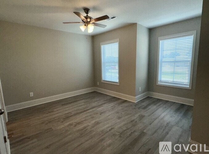 A room with a ceiling fan and wood flooring.