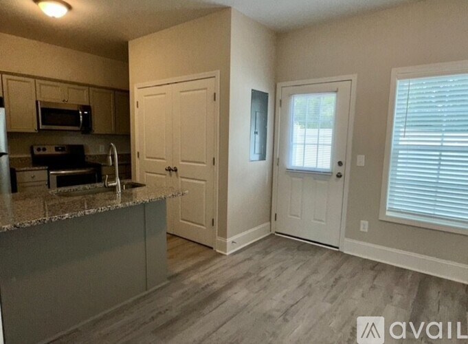 A kitchen with a granite countertop and a window with blinds.
