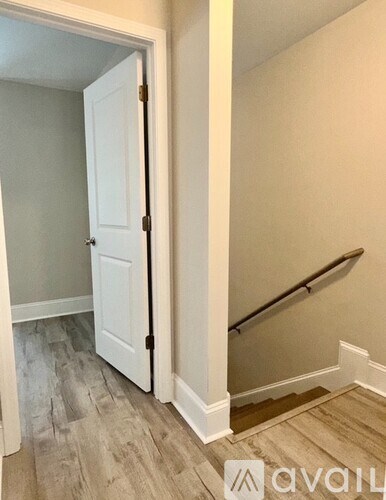 A white door is open to a hallway with a staircase.