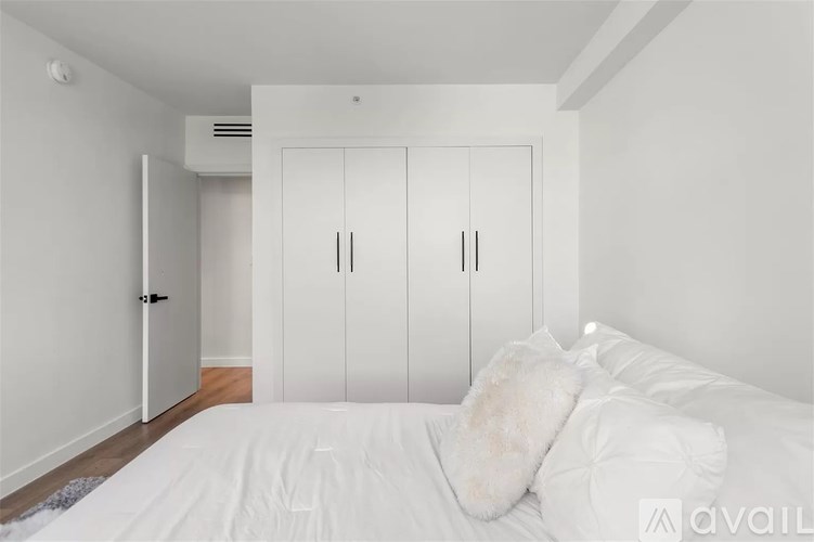 A white bedroom with a bed, pillows, and a wardrobe.