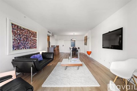 A living room with a black couch, a white chair, and a large painting on the wall.